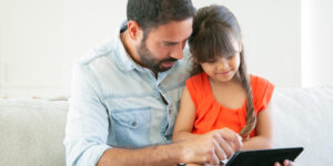Pai ensinando filha no tablet